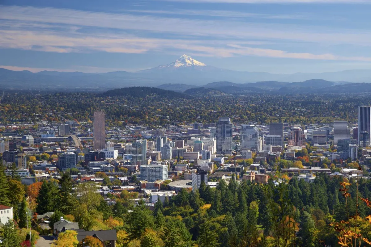 A panoramic view of the city skyline with Mount Hood in the background and lush green foreground, hinting at opportunities for hiking, exploration, and enjoying scenic vistas nearby.