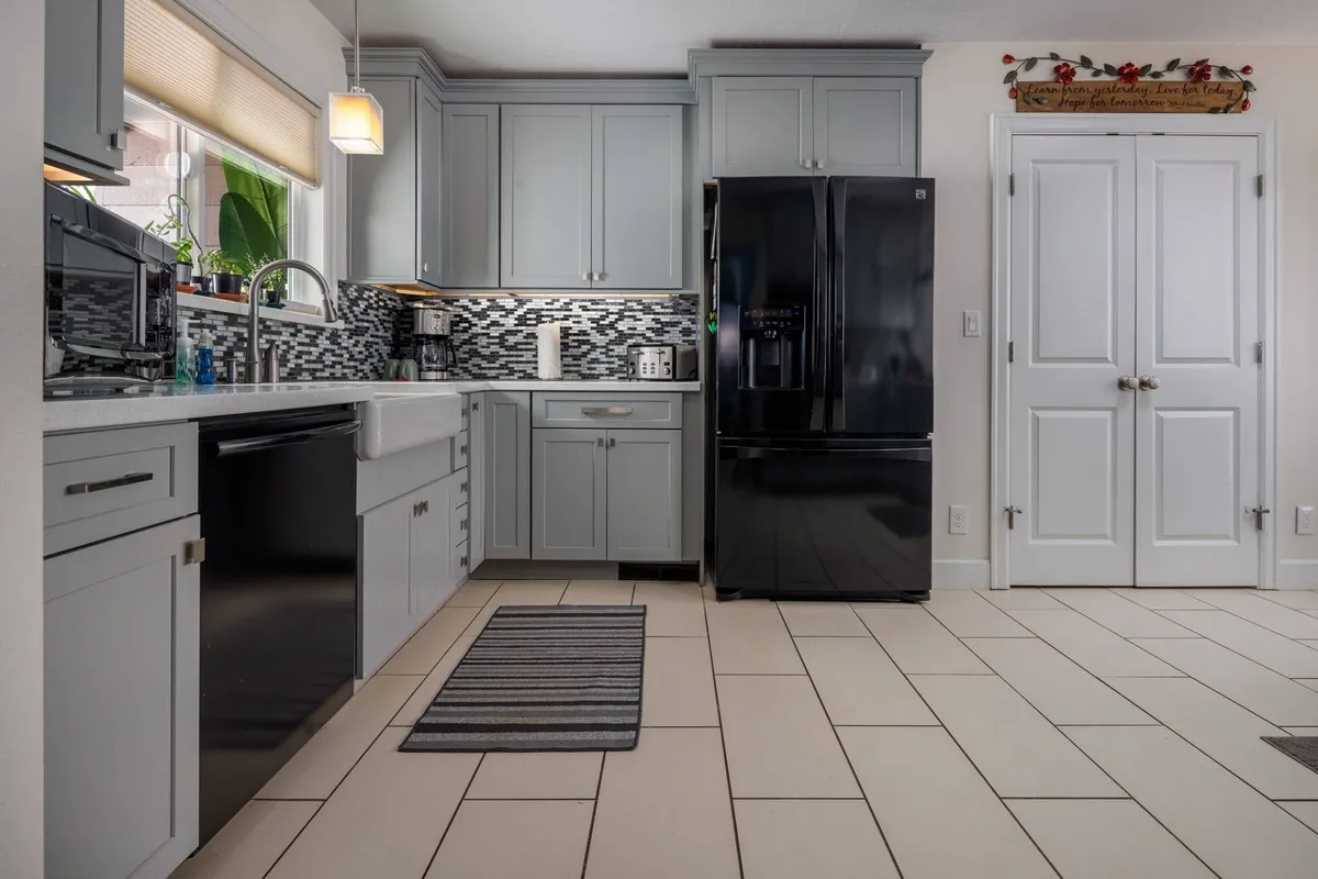 A modern kitchen with sleek cabinetry, a black refrigerator, spacious countertops, and a bright, inviting atmosphere ideal for preparing home-cooked meals or entertaining colleagues after a workday.