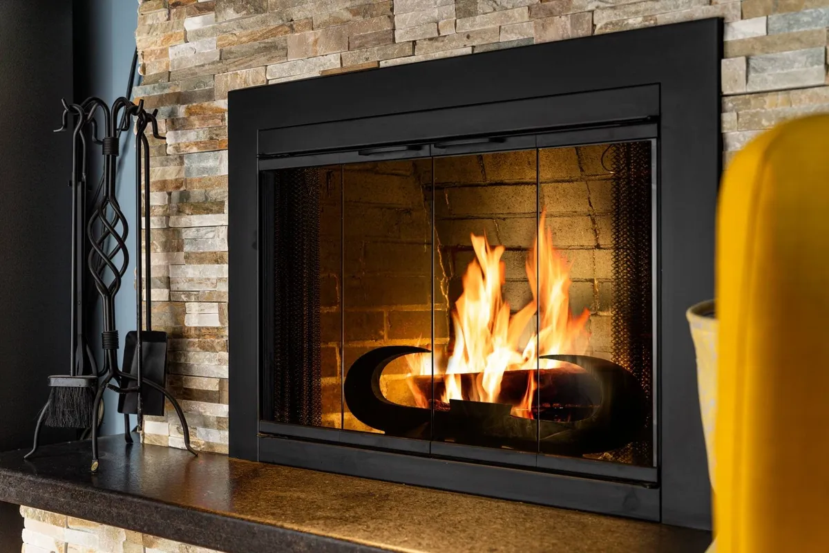 A cozy interior scene featuring a stone fireplace with glowing flames, surrounded by friends enjoying the warmth and ambiance. The space feels intimate, ideal for gathering after a day of adventures.